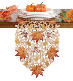 a table topped with plates covered in fall leaves and pumpkins on top of it