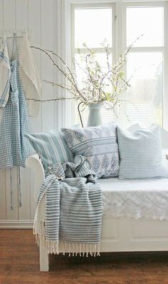 a white daybed with blue and white pillows on it in front of a window