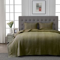 a bed with a green comforter and pillows