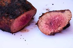 a piece of meat sitting on top of a white plate next to another piece of meat