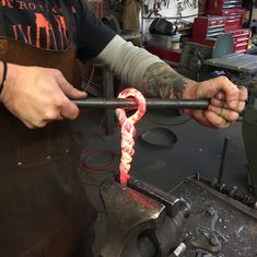 a man working on something in a shop with his arm wrapped around an object and the other hand holding it