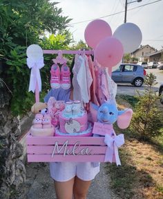 a woman holding a pink cart with balloons and items on it in front of her