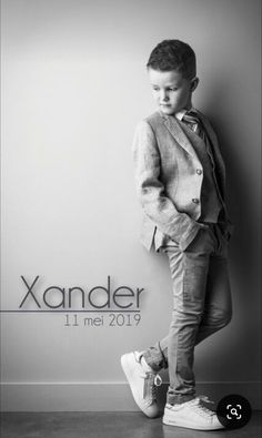 a young boy leaning against a wall with the name xander written on it