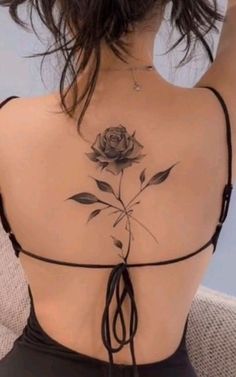 the back of a woman's body with a rose tattoo on her upper part