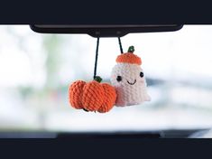 two knitted pumpkins hanging from a car mirror