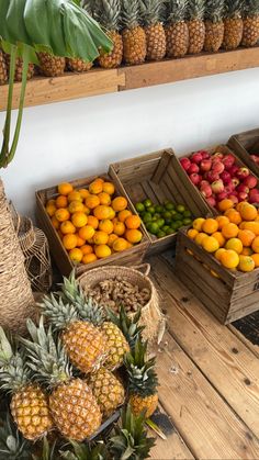 pineapples, oranges, and other fruits are on display in wooden crates