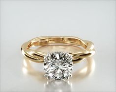 a yellow gold engagement ring with a round cut diamond in the center, on a white background