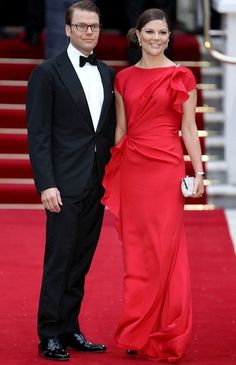 a man and woman in formal wear standing on a red carpet