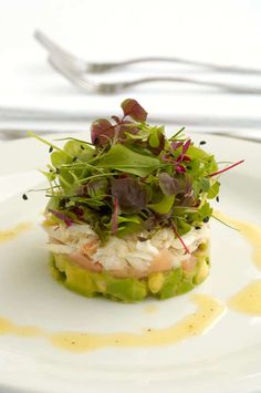 a white plate topped with a salad covered in veggies and garnish