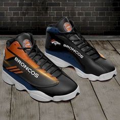 a pair of black and orange shoes sitting on top of a wooden floor next to a brick wall