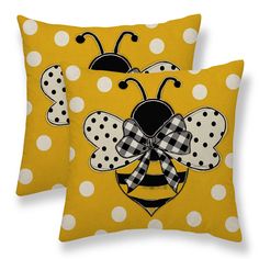 two yellow pillows with black and white polka dots on them, one has a ladybug