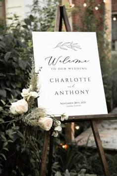 a welcome sign with flowers and greenery in front of a house for an outdoor wedding