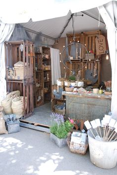 an outdoor market with lots of baskets and other items on display under a white tarp