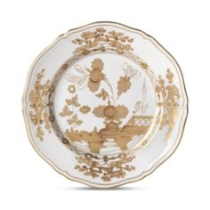 a white and gold plate with flowers on the rim, in front of a white background