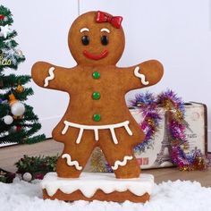 a ginger man standing in the snow next to a christmas tree