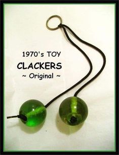 two green glass balls hanging from a black cord with the words 1970's toy clackers original