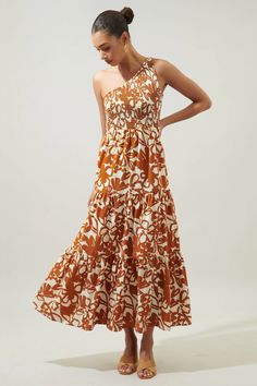 a woman is wearing an orange and white dress with flowers on the side, she has her hands on her hips