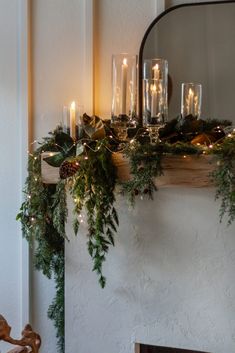 a mantel with candles, greenery and other christmas decorations on it's mantle