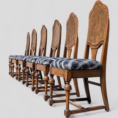 six wooden chairs lined up next to each other with plaid seat covers on the backs