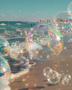 soap bubbles are floating on the beach as people swim in the water and play in the waves