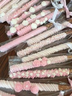 pink and white decorated cookies in cellophane wrappers on a table with ribbon