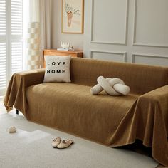 a living room with a couch covered in a blanket and two slippers on the floor