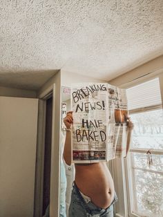 a pregnant woman holding up a newspaper with the words breaking news half baked written on it