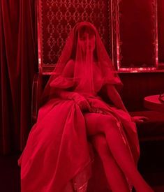 a woman in a wedding dress sitting on a bench with red light coming from behind her