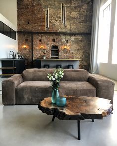 a living room with a couch, table and brick wall in the backround