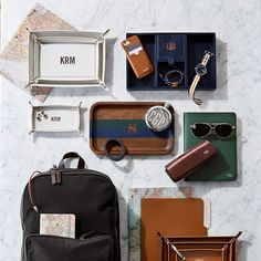 various personal items laid out on a marble counter top, including sunglasses, keys, and wallets