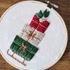 a close up of a embroidery on a hoop with a piece of ribbon and present boxes