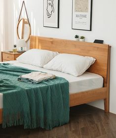 a bed with white pillows and green blanket on it in a bedroom next to two framed pictures