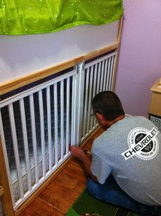 a man kneeling down next to a white radiator in a room with purple walls