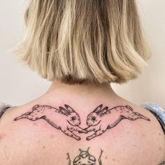 the back of a woman's neck with two rabbits on it