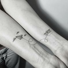 two people with tattoos on their arms and one has a paper airplane in the sky