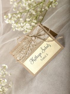 a close up of a card on a table with flowers in the background and a ribbon tied around it