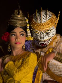 a man and woman dressed up in costumes with masks on their heads, posing for the camera