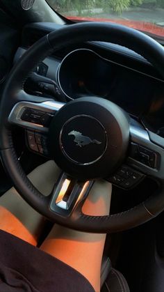 a person is sitting in the driver's seat of a car with their feet on the steering wheel