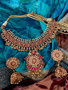 Experience opulence with our exquisite jewelry set, crafted by the same skilled artisans who create real gold pieces. Fashioned from top-quality materials, it mirrors the allure of genuine gold without the price tag. Perfect for destination weddings and parties, its elegance is matched only by its convenience and security for travel. Product Details: Material: Each piece is meticulously handcrafted from high-quality brass and Kundan Stones. Necklace Dimensions: Weight: 85 grams Closure Type: Pre Diwali Ruby Jewelry, Festive Ruby Jewelry With Intricate Design, Festive Ruby Jewelry With Elegant Design, Formal Ruby Jewelry Sets For Festivities, Elegant Gold-plated Chandbali Jewelry Sets, Elegant Gold Plated Chandbali Jewelry Sets, Elegant 22k Gold Chandbali Jewelry Sets, Festive Yellow Gold Kundan Necklace With Ruby, Elegant Round Jewelry With Stone Work