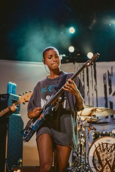 a woman holding a guitar while standing on stage