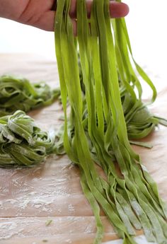 someone is cutting green beans on a wooden board