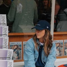 a woman sitting on a bench in front of a store window looking at her cell phone