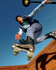 a man riding a skateboard up the side of a brick wall next to a traffic light