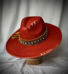 A SandalwoodandBirchCo custom item. Felt hat in smoked paprika with burned detailing. Layered hat band with feathers and custom rhinestone belt will be sure to turn heads. Hat is hand painted, stitched and burned.    This is a wide brim hat with adjustable head band. Send DM for customization. Paint Cowboy Hat, Red Fitted Hat For Festival, Fitted Red Festival Hat, Fitted Red Rodeo Hat, Fitted Red Hat For Rodeo, Red Fitted Hat For Rodeo, Red Country Hat With Curved Brim, Red Wide Brim Hat For Festival, Red Curved Brim Felt Hat For Festivals