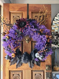 a wreath with purple flowers is hanging on the front door to decorate it for halloween