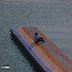 a man sitting on top of a rainbow colored dock