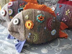 three knitted fish pillows sitting on top of a table