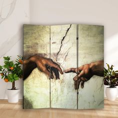 two hands touching each other in front of a painting