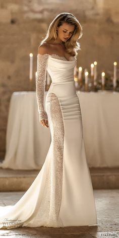 a woman in a white dress posing for the camera with candles on the table behind her