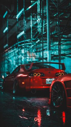 a red sports car parked in front of a building with its lights on at night